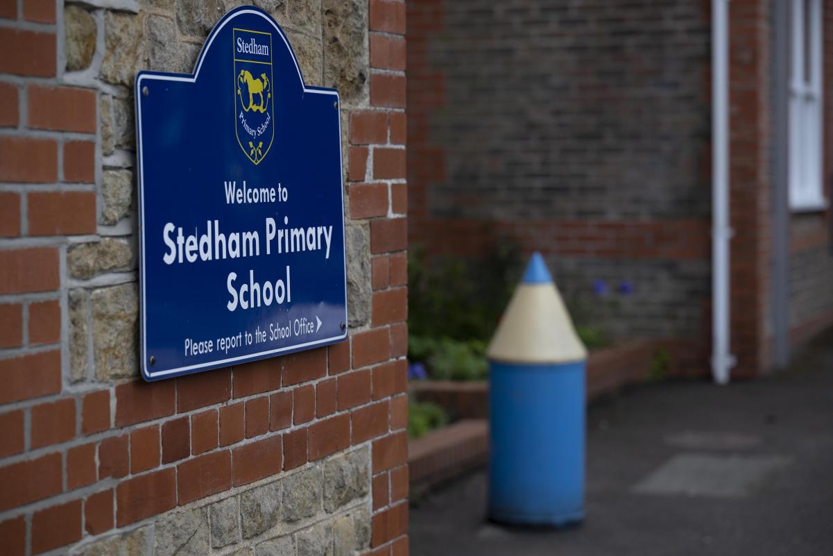 The welcome sign at the entrance to Stedham Primary School, with a pencil-shaped bollard alongside
